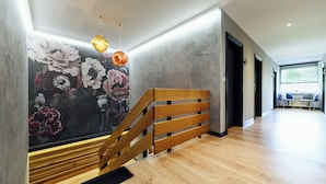 Una escalera moderna con escalones de madera y barandilla metálica, que conduce a una habitación con un mural floral en la pared.