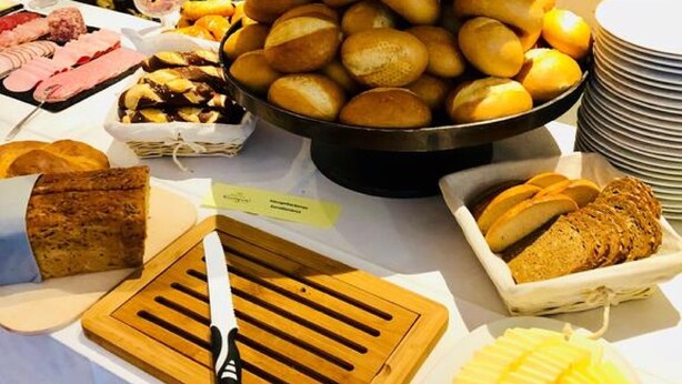 Un bufé con panes, pasteles y una bandeja de frutas.