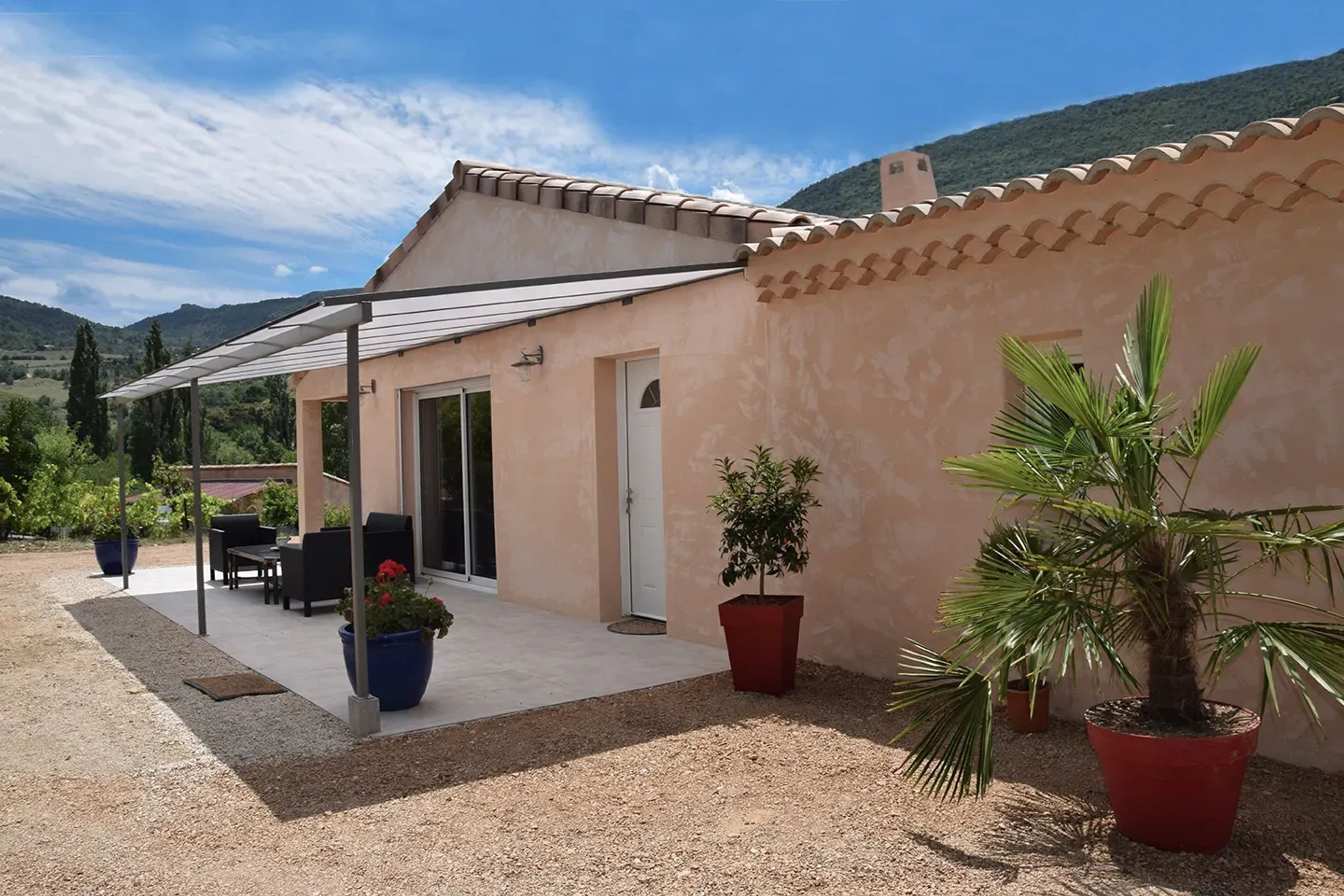 A house with a covered patio, a door, and potted plants.