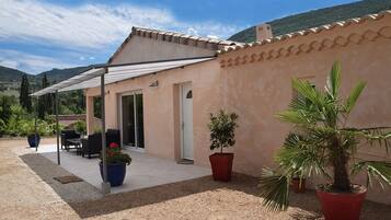 A house with a covered patio, a door, and potted plants.