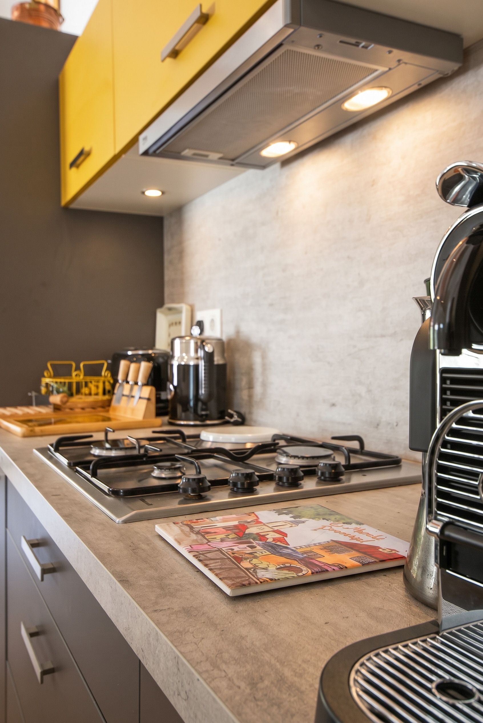 Une cuisine équipée d’une cuisinière à gaz, d’une machine à café et d’un gril.