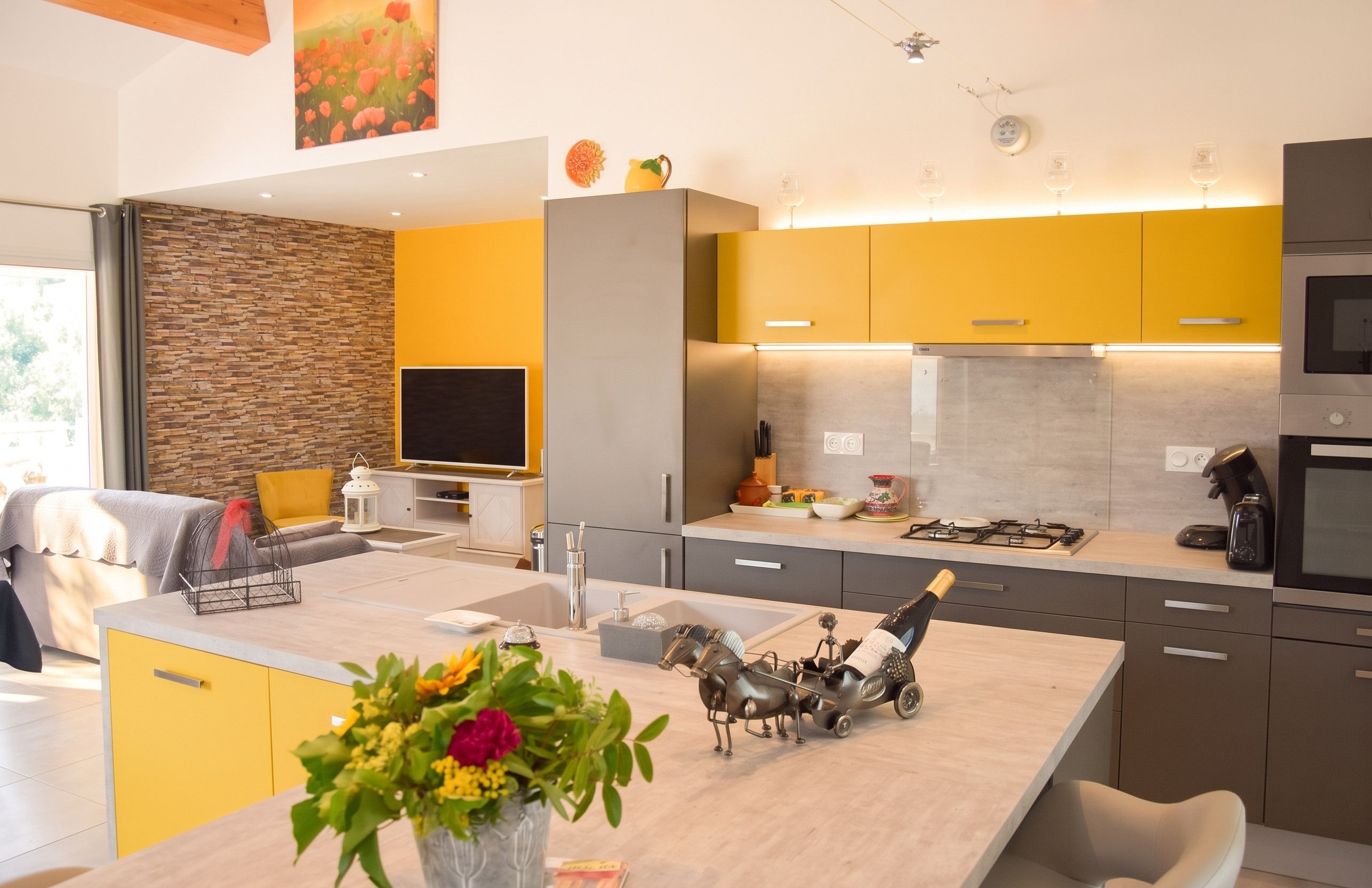 A modern kitchen with a central island, built-in appliances, and a stone accent wall.