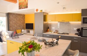 A modern kitchen with a central island, built-in appliances, and a stone accent wall. - Homerez - House, La Roche-sur-le-Buis. (La Roche-sur-le-Buis)