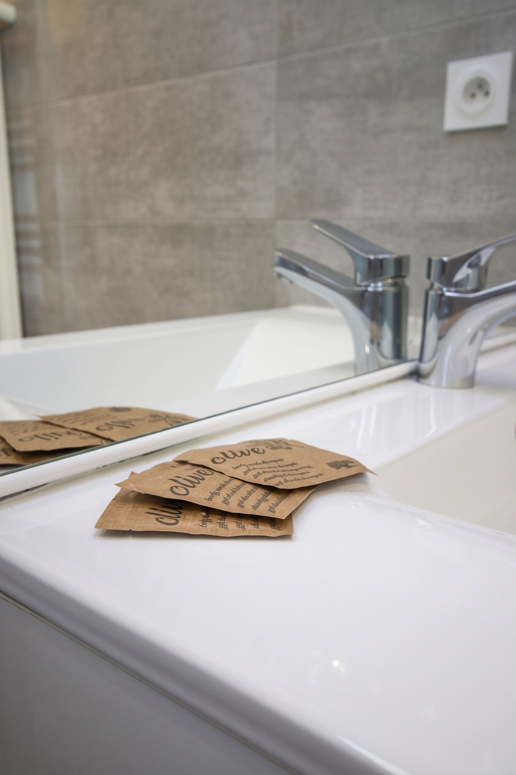 A bathroom with a white sink, a mirror, and a faucet. There are brown paper bags with text on the sink.