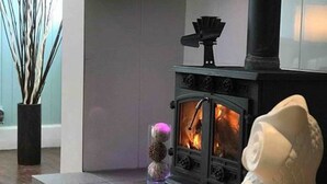 A modern living room with a wood-burning stove, a decorative owl, and a chessboard on a wooden table. - Vollie House (Thornhill)