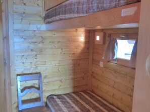 A small, wooden cabin room with a bunk bed, a window, and a small table. - Sunny 2/3 room apartment for 6 people in Méribel Altiport (Méribel)