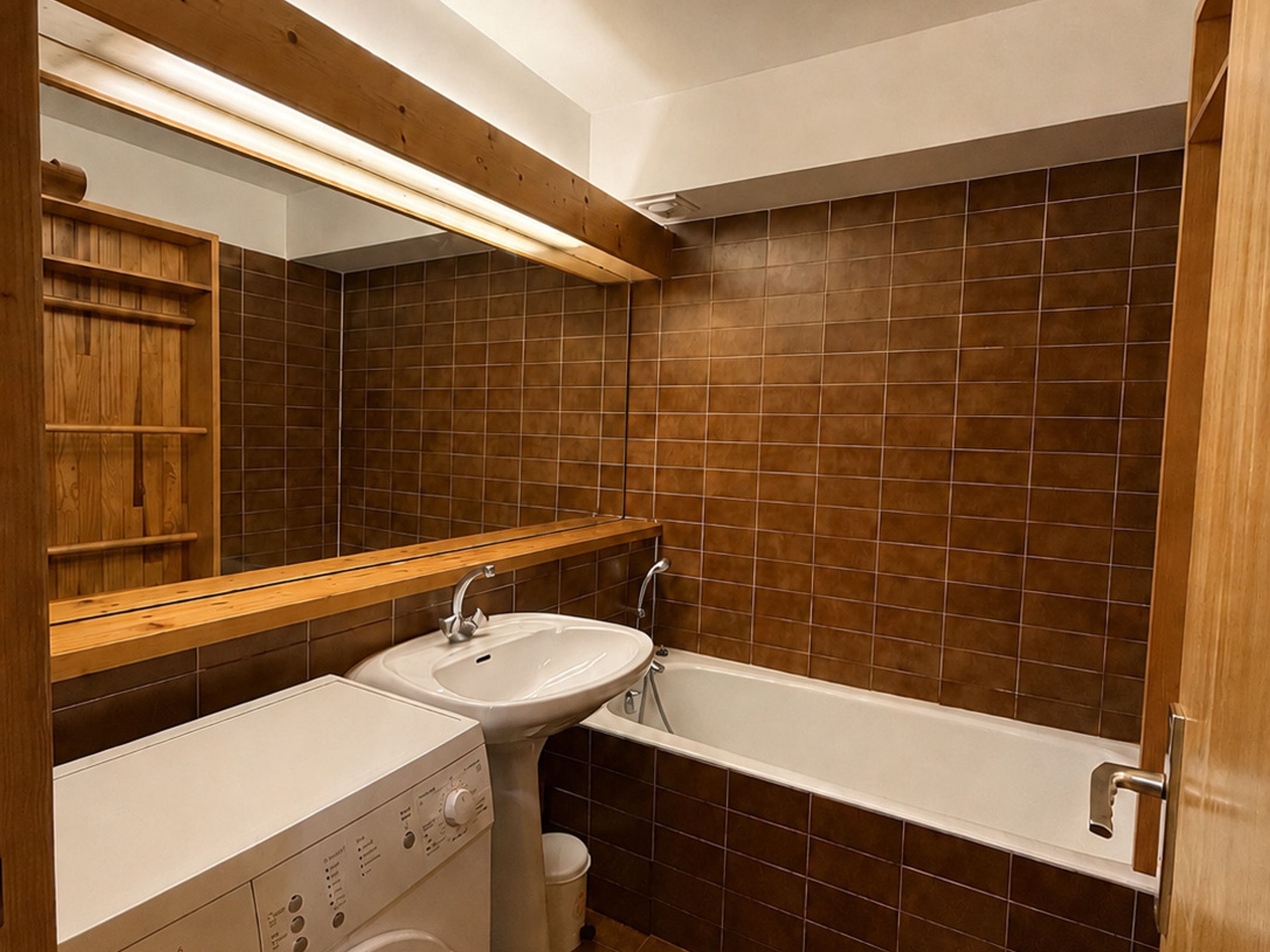 Een badkamer met een houten wastafelmeubel, een wastafel, een bad en een spiegel.