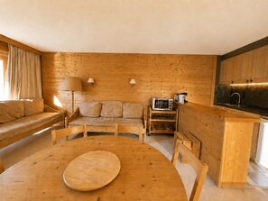 A wooden interior with a round table, sofa, and kitchenette. - Sunny 2/3 room apartment for 6 people in Méribel Altiport (Méribel)