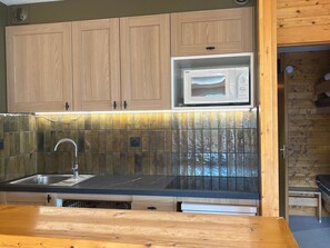 A kitchen with wooden cabinets, a stainless steel sink, a microwave, and a wooden countertop. - Sunny 2/3 room apartment for 6 people in Méribel Altiport (Méribel)