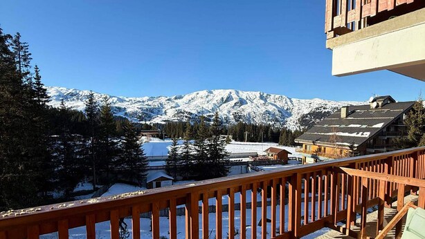Ein Balkon mit Blick auf schneebedeckte Berge und Gebäude.