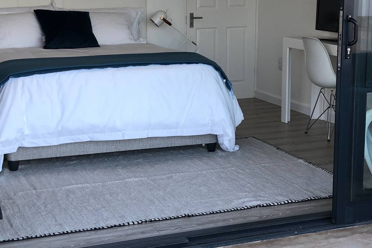 A bedroom with a bed, a desk, and a chair.