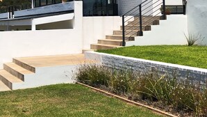A modern house with a unique sloped roof, large windows, and a staircase leading to the entrance. - Karee Manor Guesthouse (Still Bay)