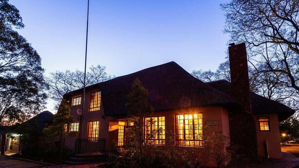 A two-story house with a thatched roof, multiple windows, and a chimney. - Matalatala (Cullinan)