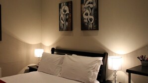 Een hotelkamer met een bed, twee bedlampen en twee abstracte schilderijen aan de muur.