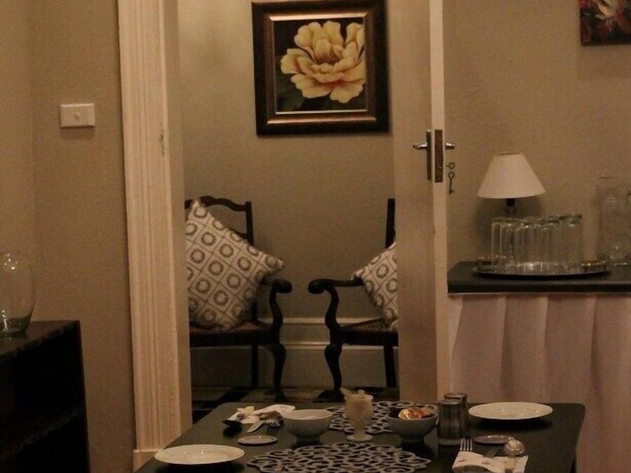 Ein Essbereich mit einem Tisch für zwei Personen, einem gerahmten Blumenbild an der Wand und einer Lampe auf einem Beistelltisch.
