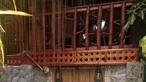 Una persona en un jacuzzi con una estructura de madera y paredes de piedra al fondo.