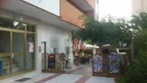 Um edifício com fachada, uma bicicleta estacionada na frente e uma pequena área de jardim com plantas.