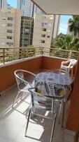 Un piccolo balcone esterno con un tavolo rotondo e due sedie, circondato da una ringhiera in metallo.