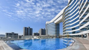 A modern building with a curved facade and a swimming pool in front. - Wyndham Grand Plaza Royale Yuzhou Xiamen (Xiamen)