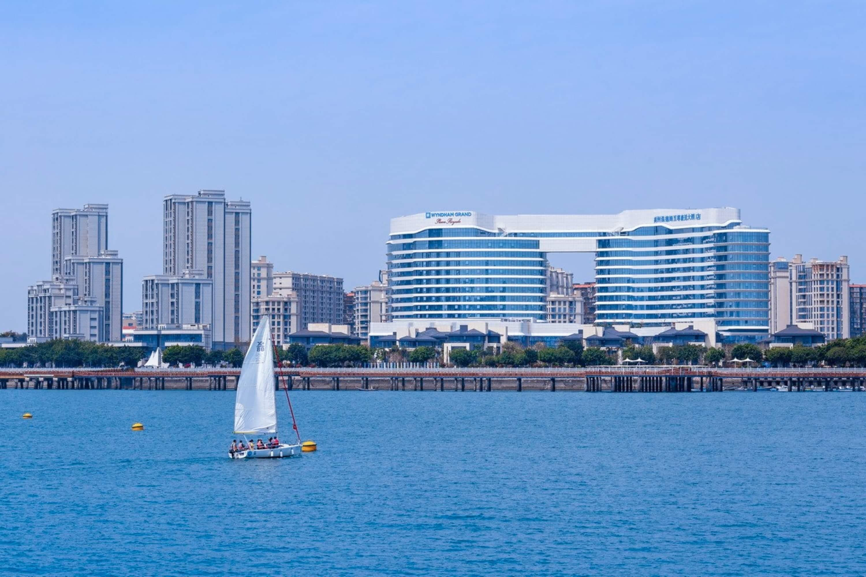 Paisaje urbano frente al mar con modernos rascacielos, incluyendo un hotel destacado con una fachada azul y blanca llamativa.