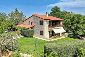 A two-story house with a stone facade, a red-tiled roof, and a balcony with a wooden railing. - Orange Grove Villa (Nafplio)