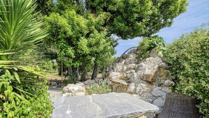 A stone bench in a garden with various plants and trees. - Orange Grove Villa (Nafplio)