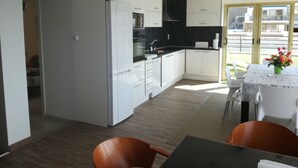 Una cucina moderna con mobili bianchi, un piano di lavoro nero e un'area da pranzo con tavolo e sedie.