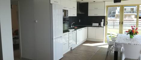 Una cocina moderna con armarios blancos, encimera negra y comedor con mesa y sillas.