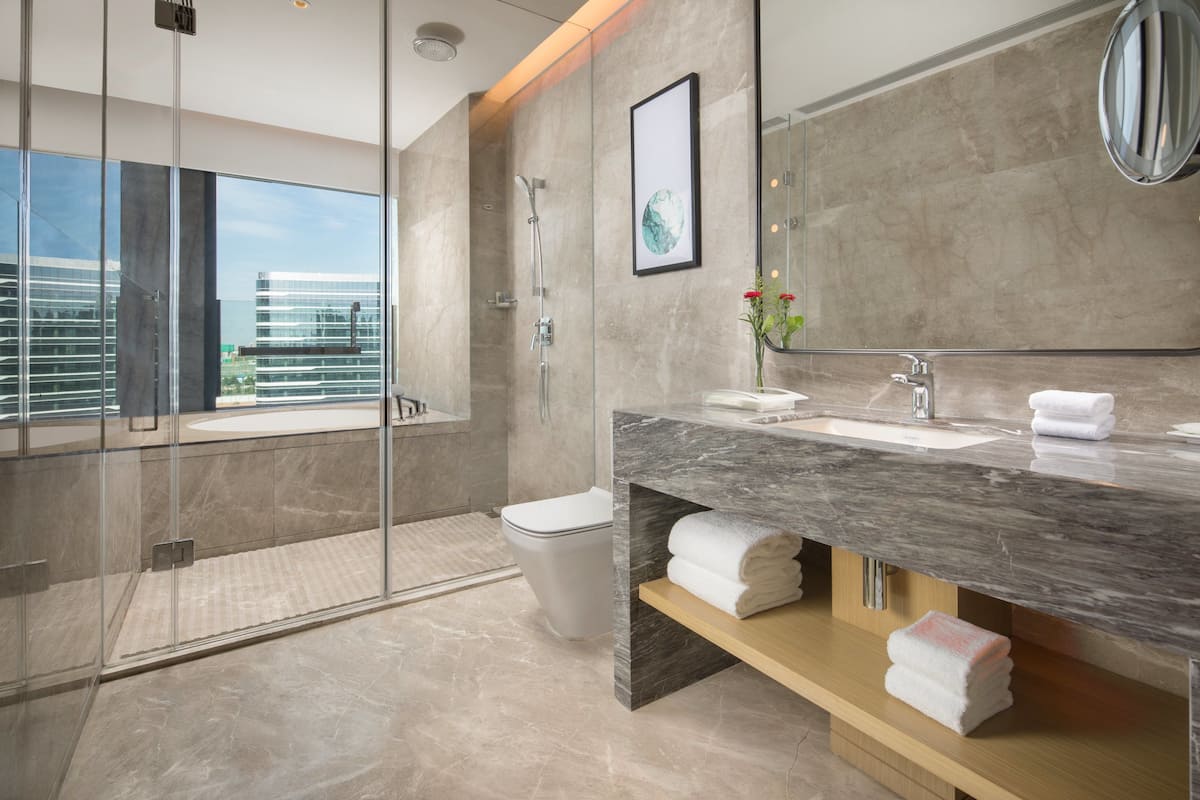 A modern bathroom with a glass-enclosed shower, a marble sink, and a large mirror.
