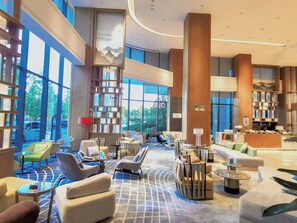 A spacious lobby with modern furniture, large windows, and a central column with a logo. - Holiday Inn Zhengzhou Riverside by IHG (Zhengzhou)