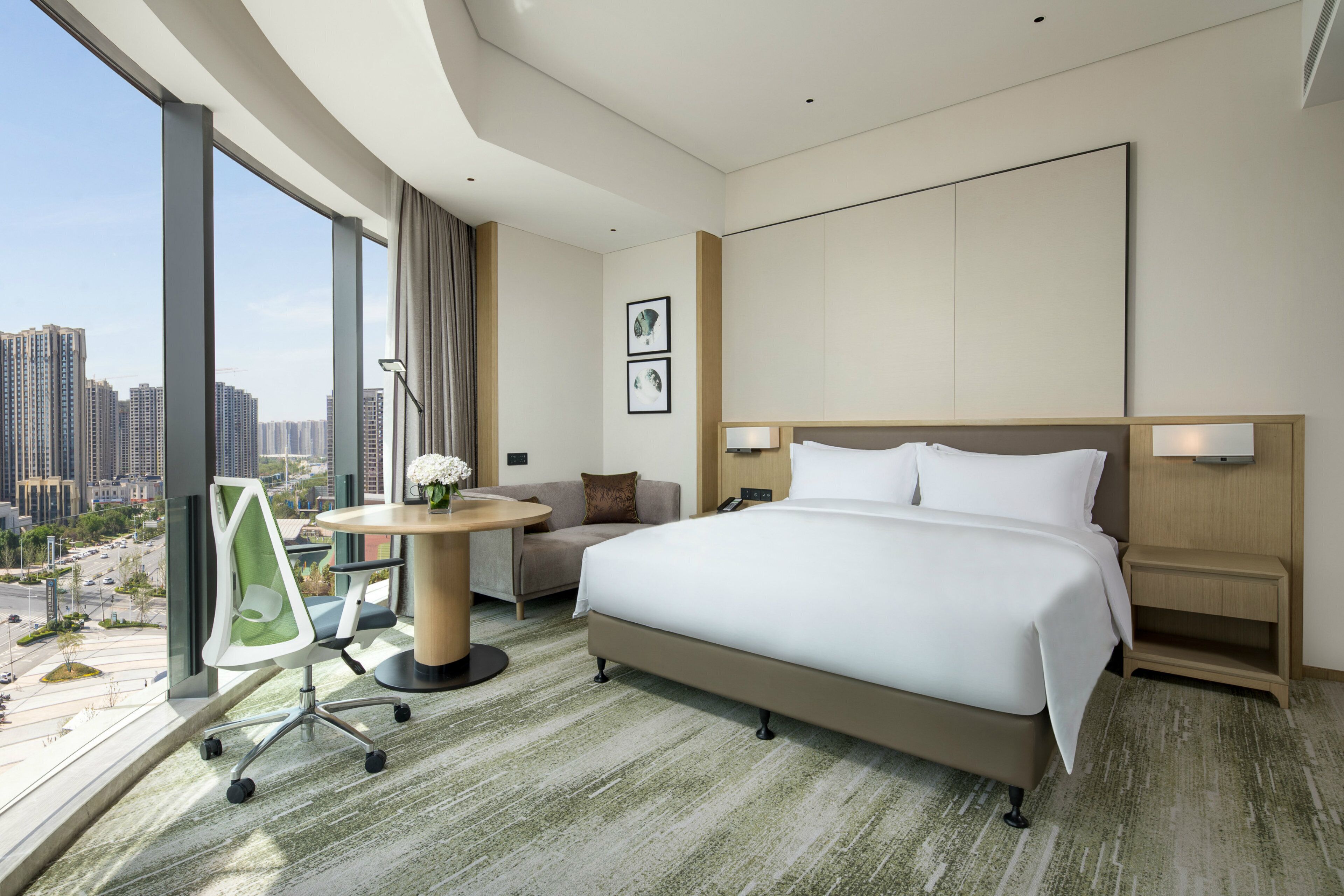 Een hotelkamer met een groot bed, een bureau, een stoel en uitzicht op de stad.