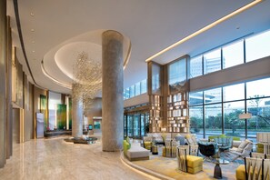 A spacious lobby with a large marble column, modern furniture, and a view of the city through large windows. - Holiday Inn Zhengzhou Riverside by IHG (Zhengzhou)