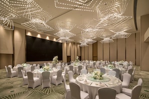 A banquet hall with round tables, white chairs, and a large screen. - Holiday Inn Zhengzhou Riverside by IHG (Zhengzhou)