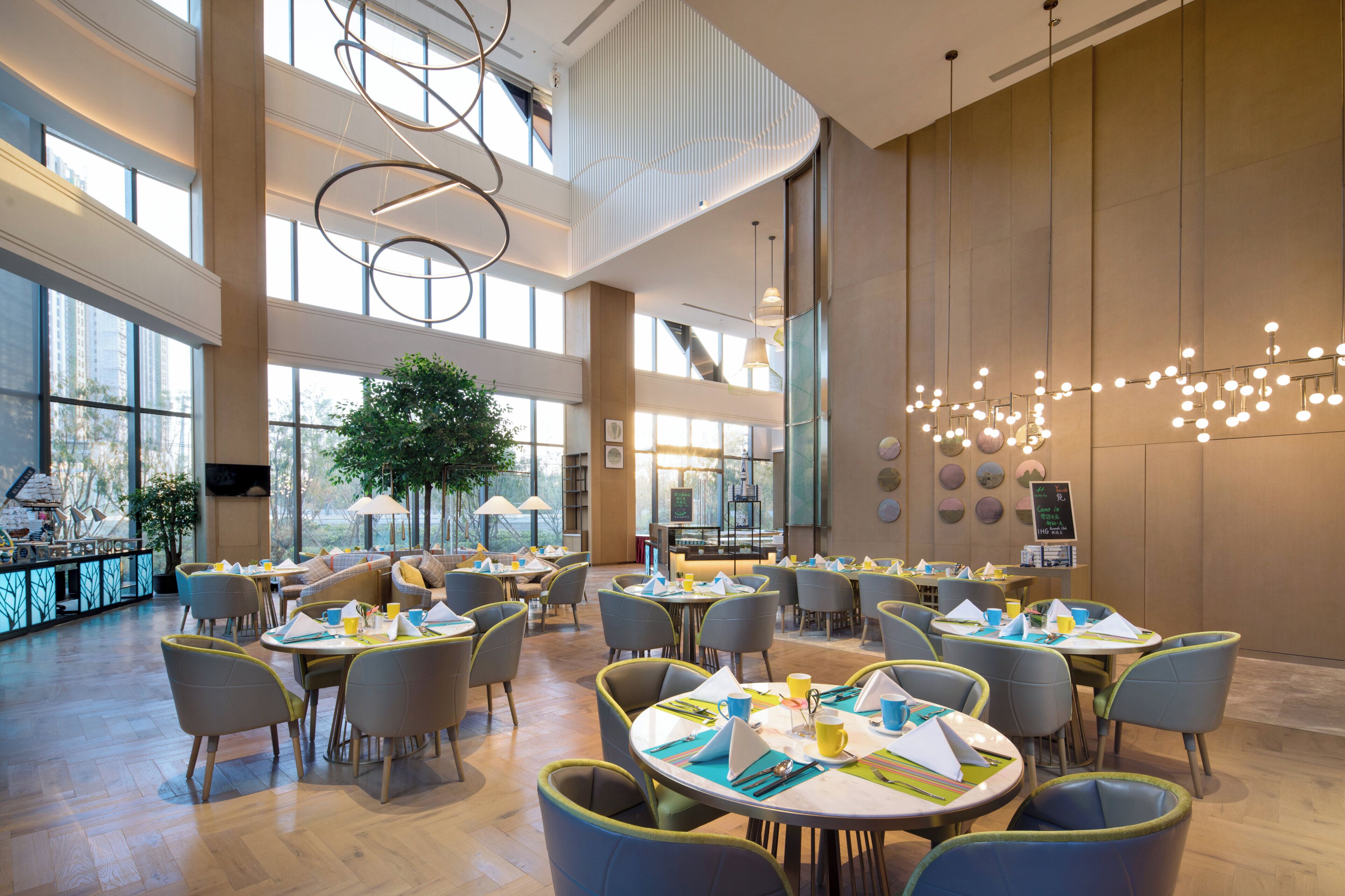 A spacious indoor dining area with high ceilings, large windows, and modern lighting fixtures.
