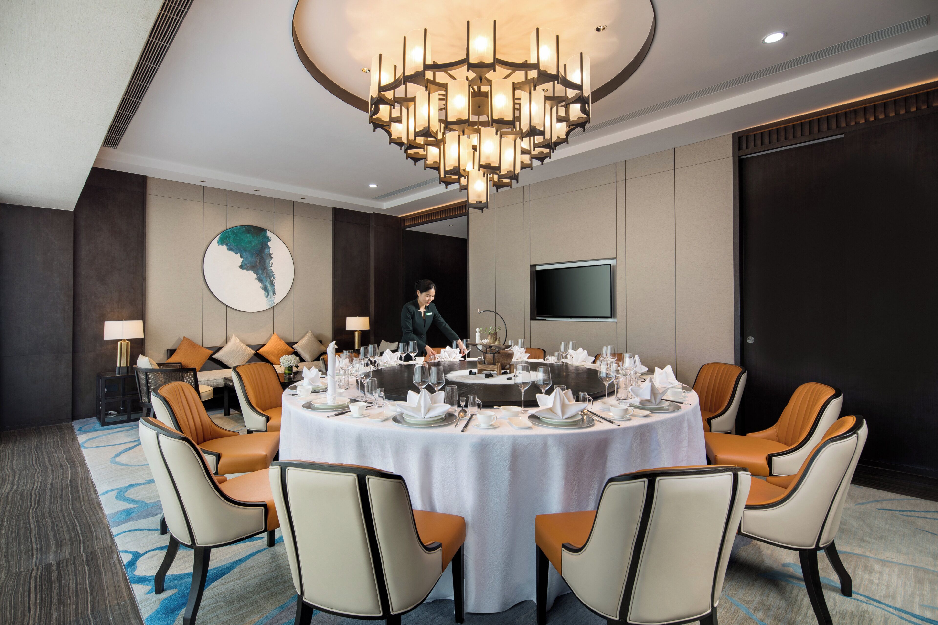 Un comedor de hotel con una mesa redonda dispuesta para una comida, rodeada de sillas, un candelabro y un gran globo terráqueo colgado en la pared.