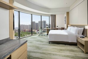 Una habitación de hotel moderna con una cama grande, un escritorio y vistas a rascacielos.