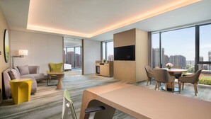 A modern hotel room with a large bed, a desk, and a dining area. There is a TV mounted on the wall and a large window offering a city view. - Holiday Inn Zhengzhou Riverside by IHG (Zhengzhou)