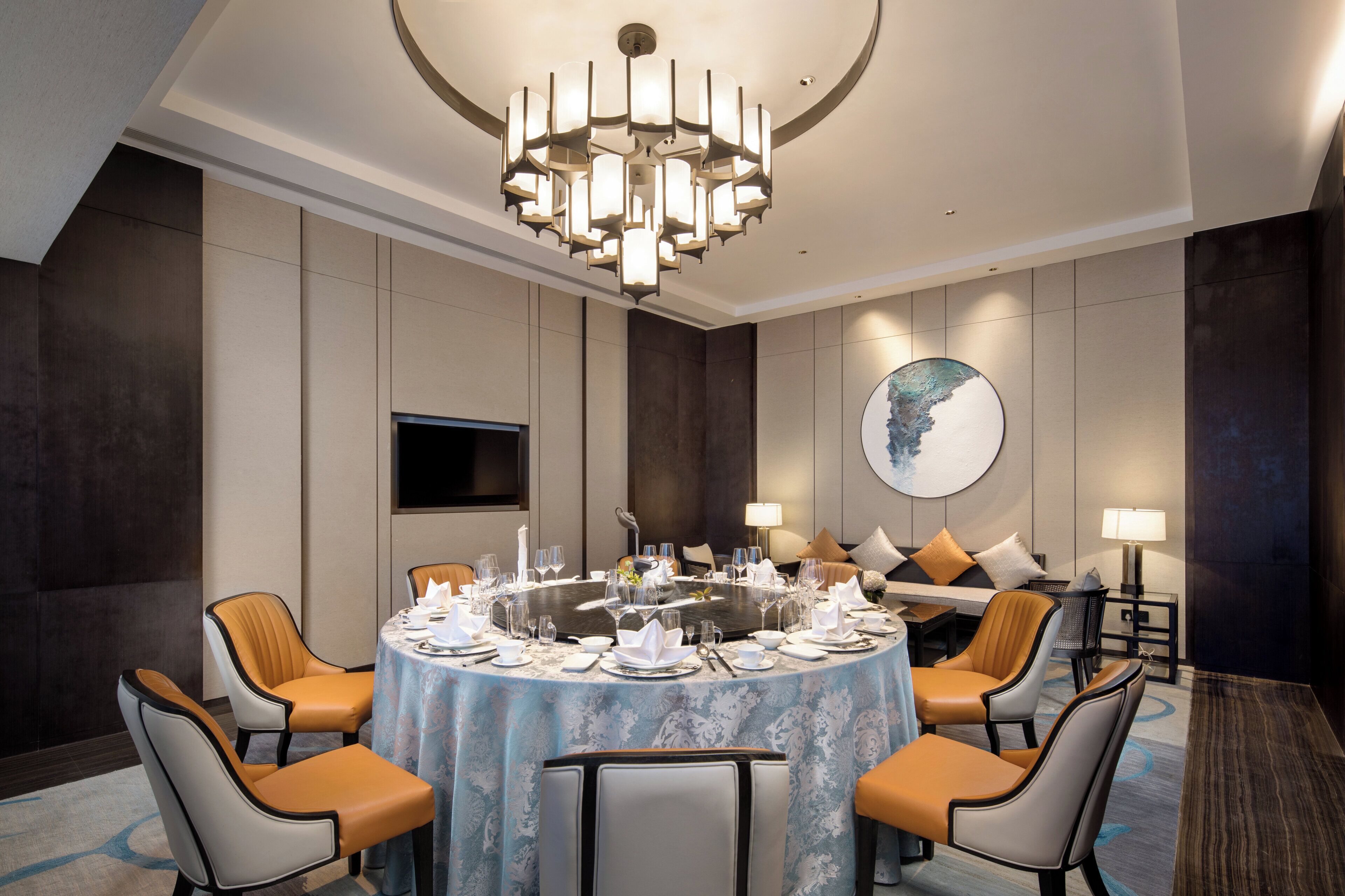 A conference room with a round table, chairs, and a chandelier.