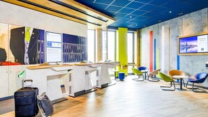 Un hall d’hôtel moderne avec un comptoir d’accueil, un espace salon et une grande fenêtre.