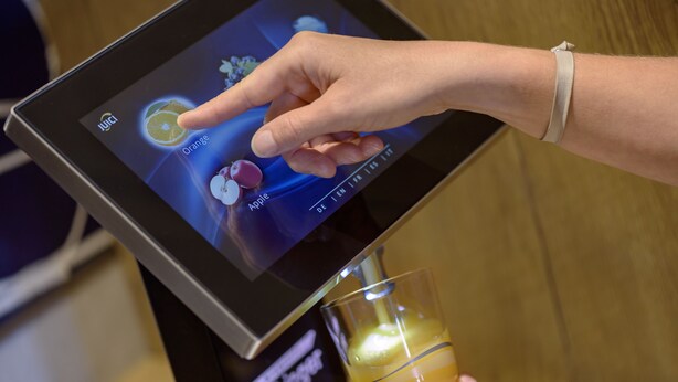 Una persona usando un quiosco con pantalla táctil para elegir una bebida del menú.