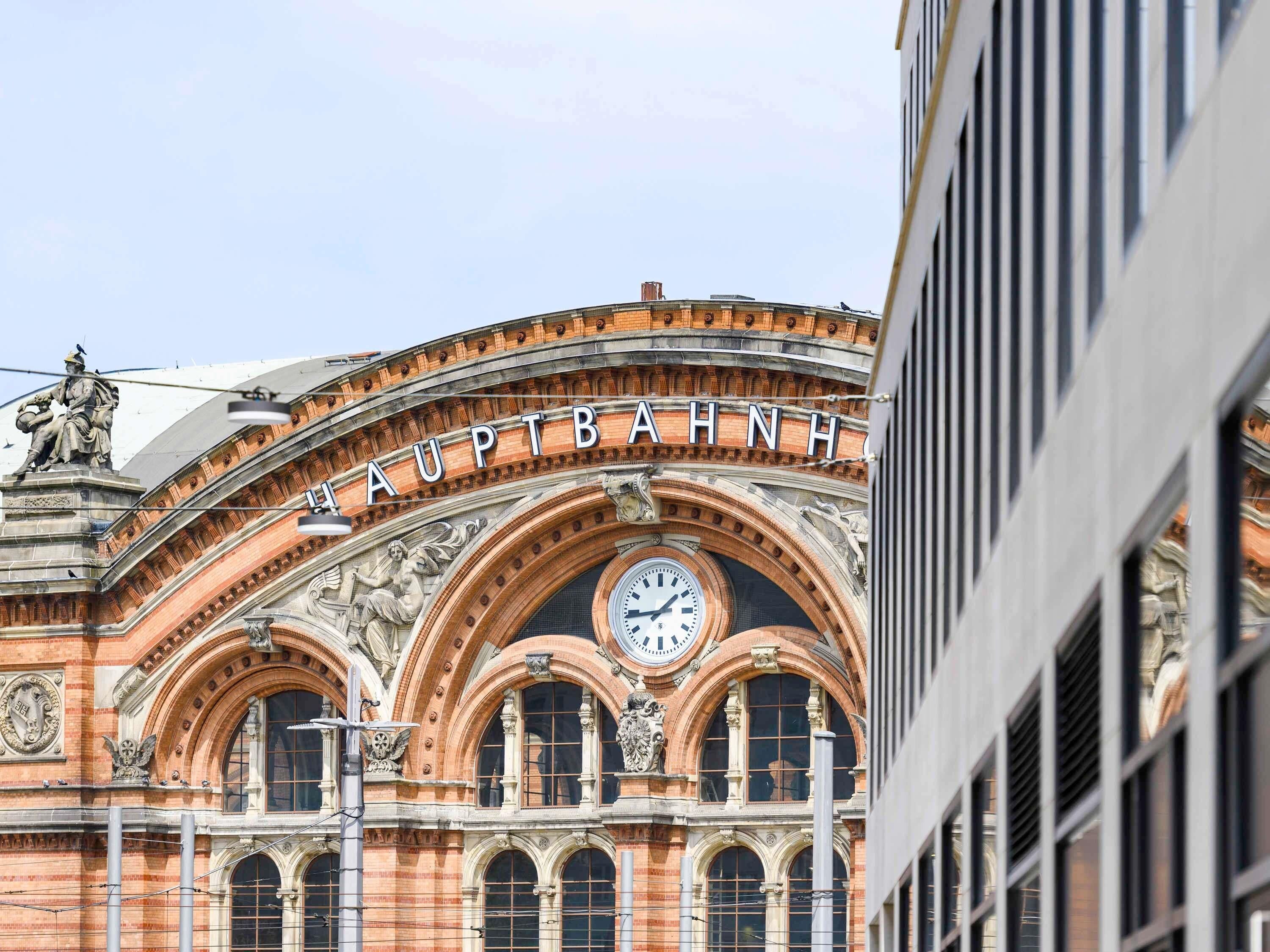Un edificio histórico con un reloj, arcos ornamentales y una estatua en el tejado.