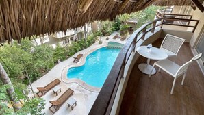 Zona de piscina con sillones de descanso, una mesa y una estructura de techo de paja.