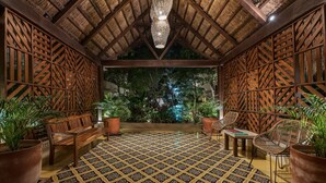 Un espacio interior con piso estampado, muebles de madera y techo de paja.