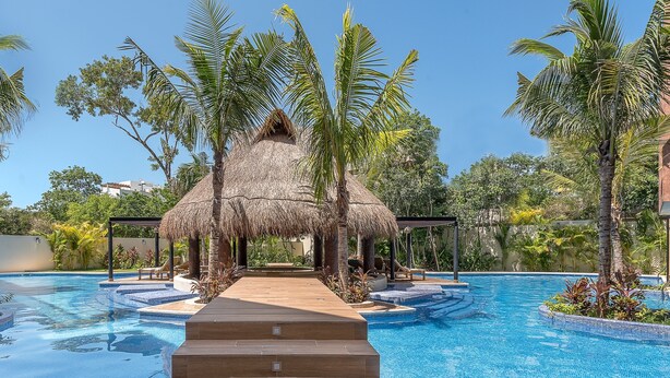 A swimming pool with a wooden staircase leading to a thatched-roof structure surrounded by palm trees. - Paramar Terra by Tulumeando (Tulum)