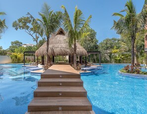 Una piscina con una escalera de madera que lleva a una estructura de techo de paja rodeada de palmeras.