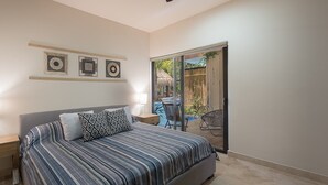 A bedroom with a bed, a ceiling fan, a nightstand, and a view of an outdoor area with a chair and a table. - Paramar Terra by Tulumeando (Tulum)