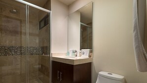 A modern bathroom with a glass-enclosed shower, a vanity with a mirror, and a toilet. - Paramar Terra by Tulumeando (Tulum)