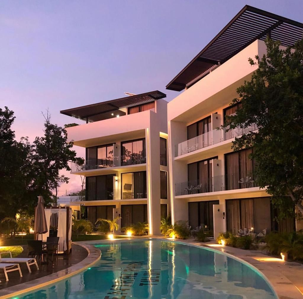 A modern hotel with a swimming pool, multiple balconies, and a well-lit outdoor area.