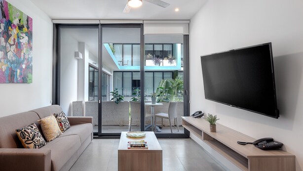 A modern living room with a sofa, coffee table, and a TV mounted on the wall.