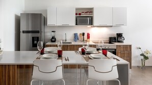 A modern kitchen with white cabinetry, a stainless steel refrigerator, a microwave, and a coffee maker.